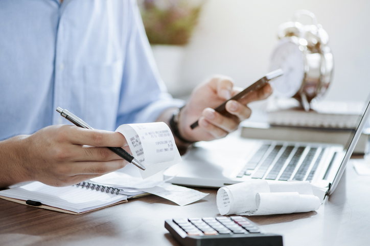 Young man holding pen with bills working for calculate business data, taxes, bills payment.