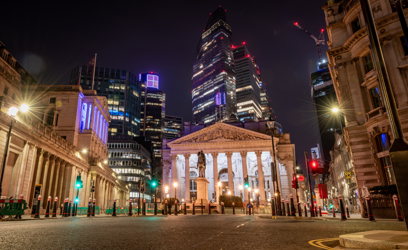 A night time view of the City of London showing the Royal Exchange, Bank of England and skyscrapers in the background.